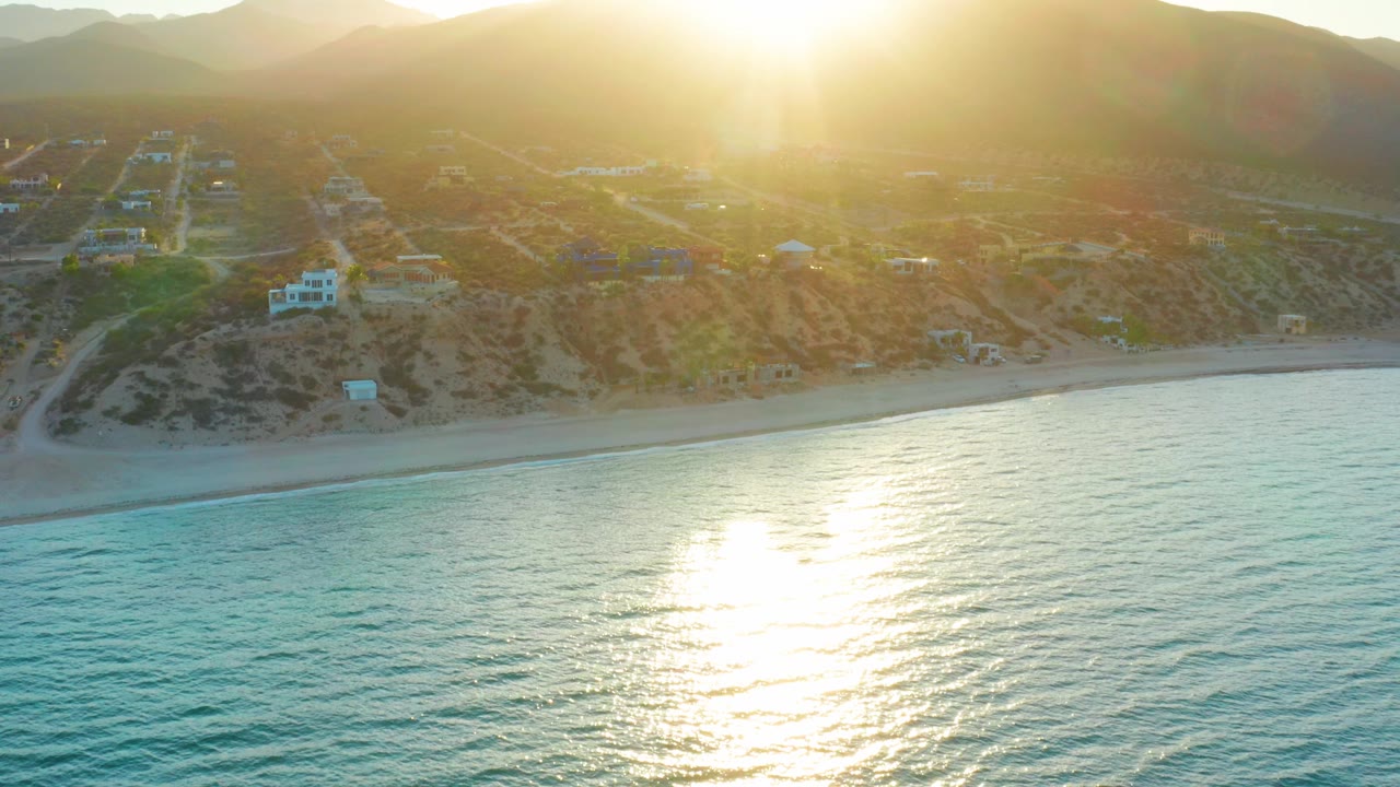 Golden glare on sea with coastline and dry hills behind