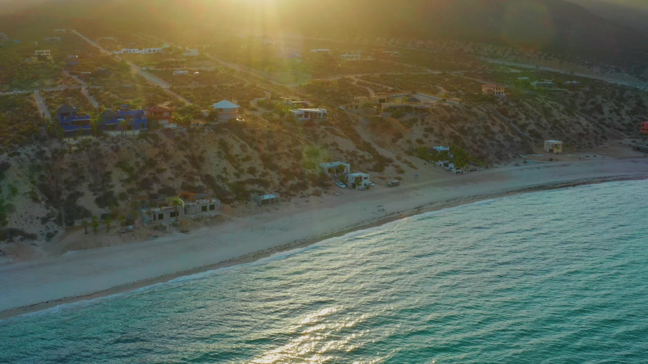 Aerial view of beach houses and reflective ocean at sunset