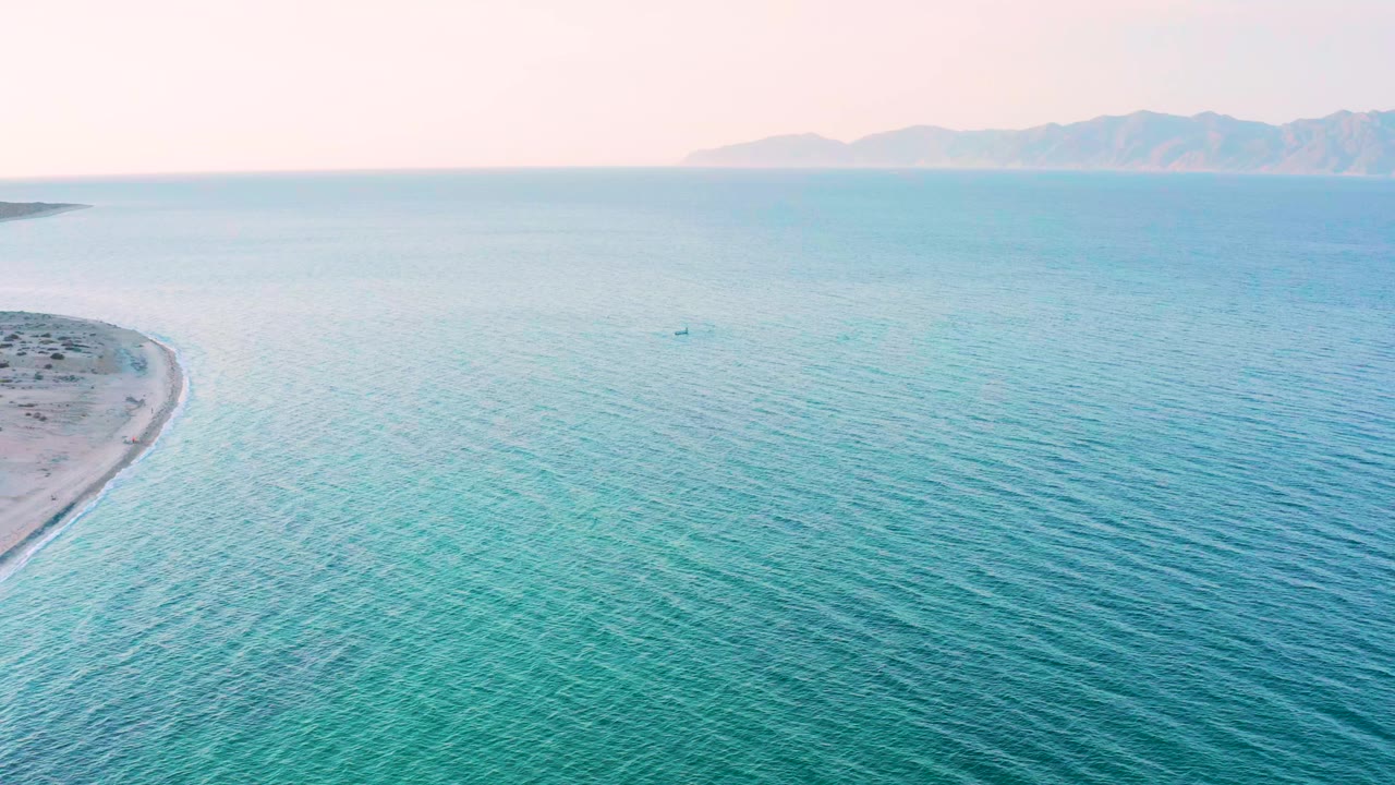 Opening frame from El Sargento La Ventana, Mexico showing rippled turquoise water, a pale sandy shoreline entering at left, distant mountains, and no visible people.