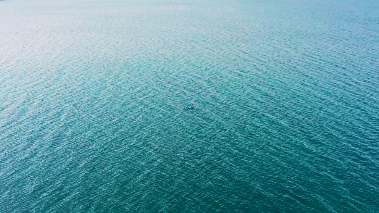Overhead view of turquoise ocean in El Sargento La Ventana, Mexico, where the small boat-like object sits against slightly darker rippled water, no visible people.