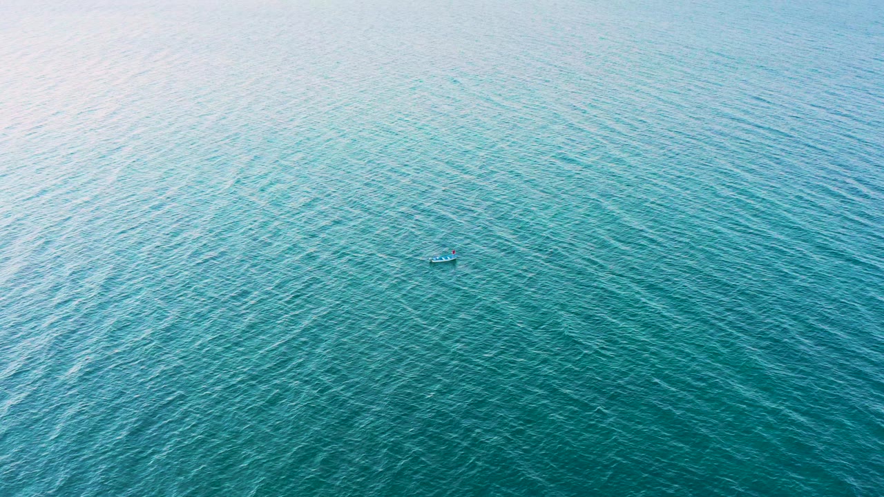 Aerial view of bright aqua water in El Sargento La Ventana, Mexico, with dense ripple lines and the small boat-like object sitting below center, no visible people.