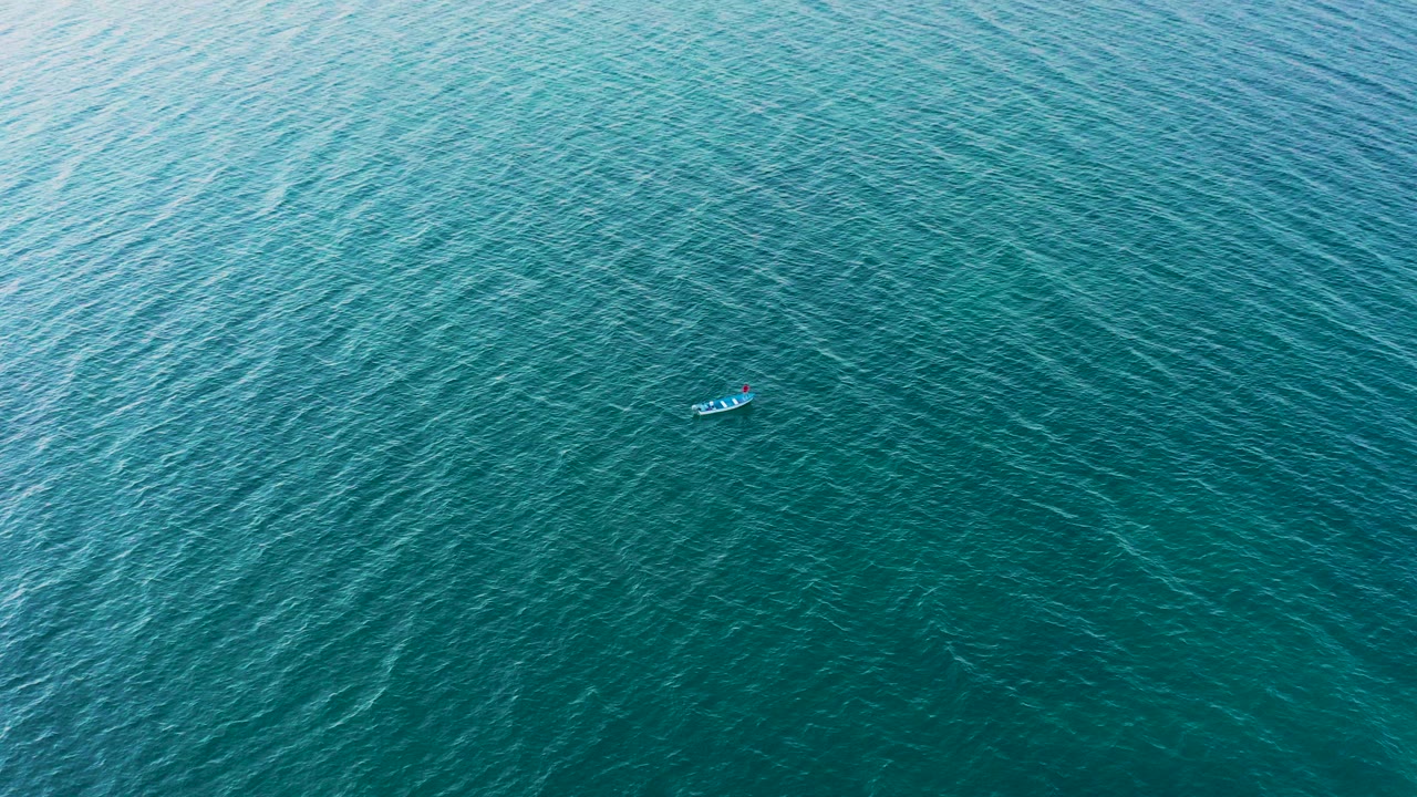 A small fishing boat sits in the upper part of a top-down view over turquoise sea in El Sargento La Ventana, Mexico, with no visible people.
