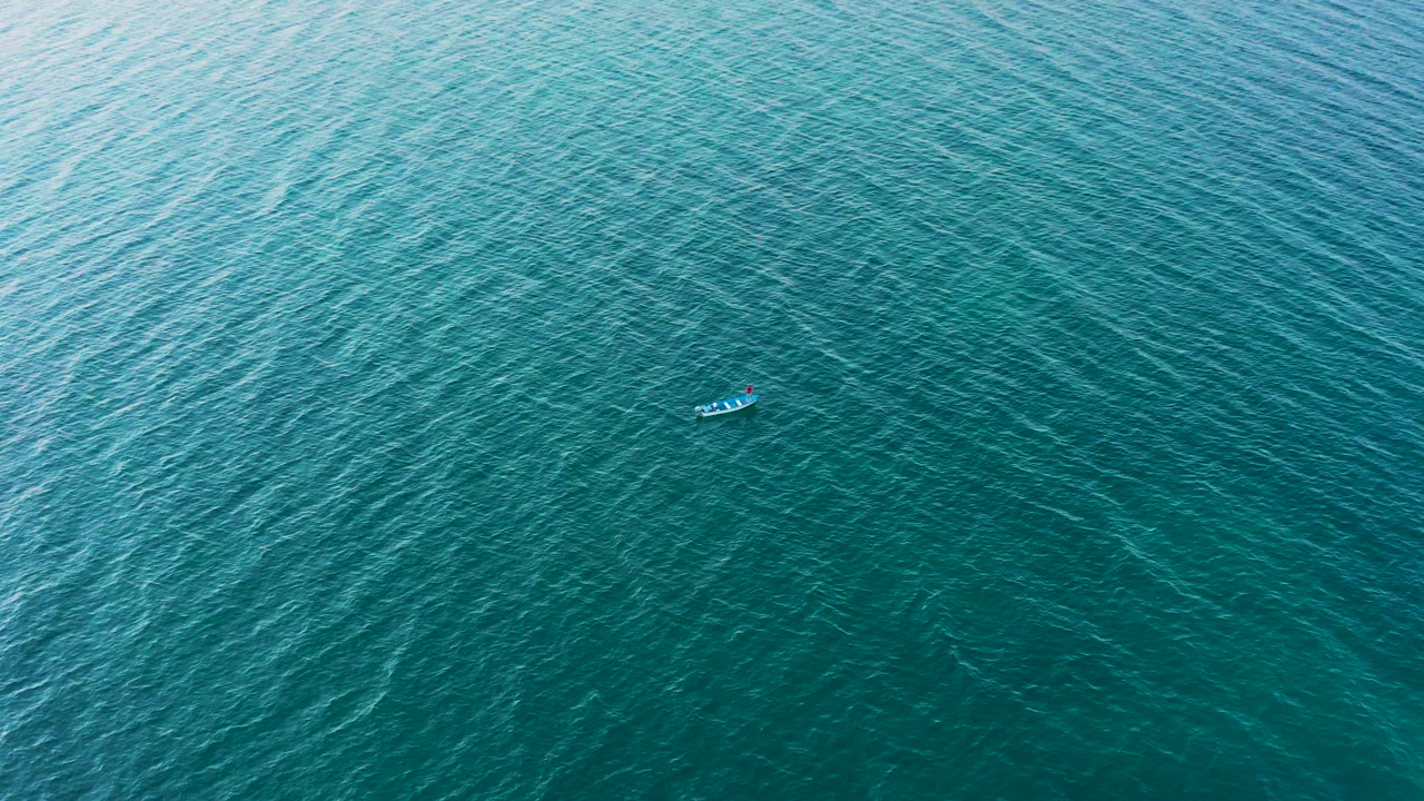 A distant small boat appears near the upper center of textured blue-green ocean water in El Sargento La Ventana, Mexico, with no visible people.