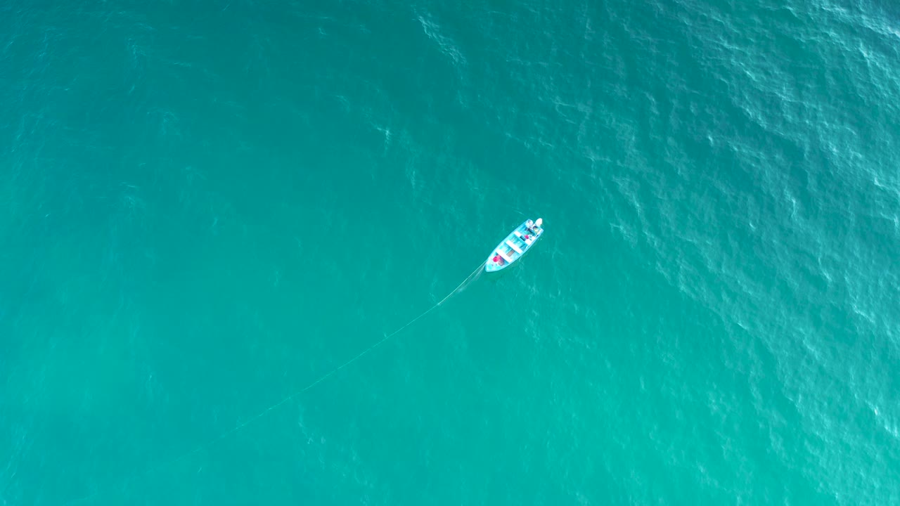 Overhead still of the sailboat over rippled clear ocean in El Sargento La Ventana, Mexico, with the boat offset left and no visible people.