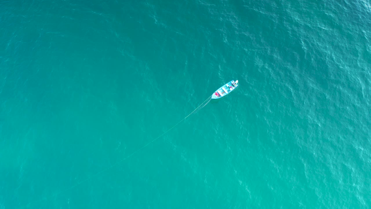 Top-down view of a small white boat near the upper left of blue-green ocean water in El Sargento La Ventana, Mexico, with no visible people.