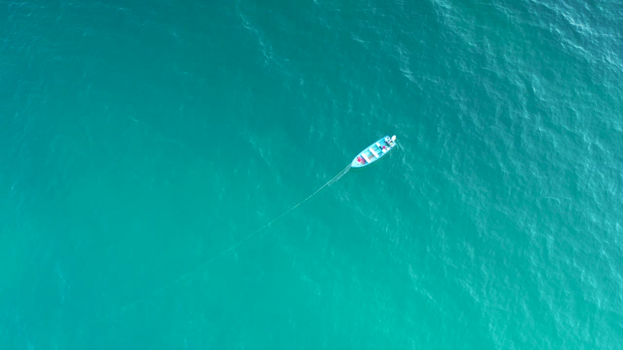 Small white boat on turquoise ocean from above