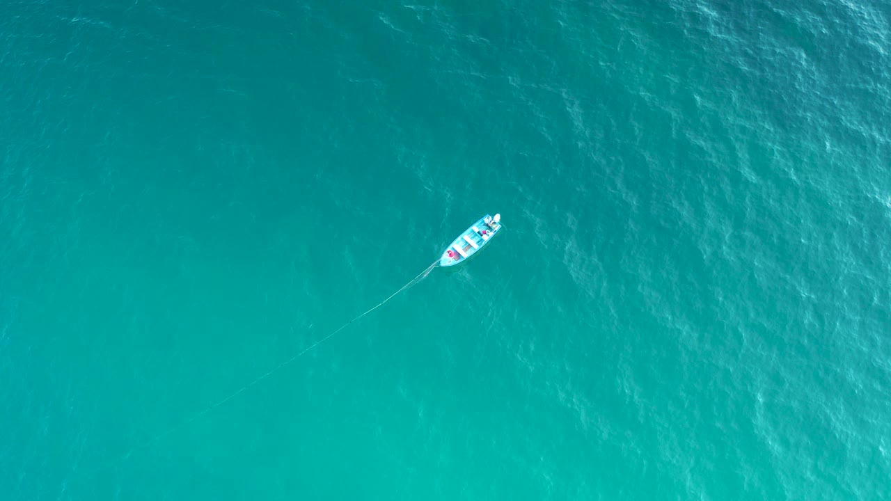 Overhead view of a small boat near the upper left of turquoise water in El Sargento La Ventana, Mexico, with no visible people.