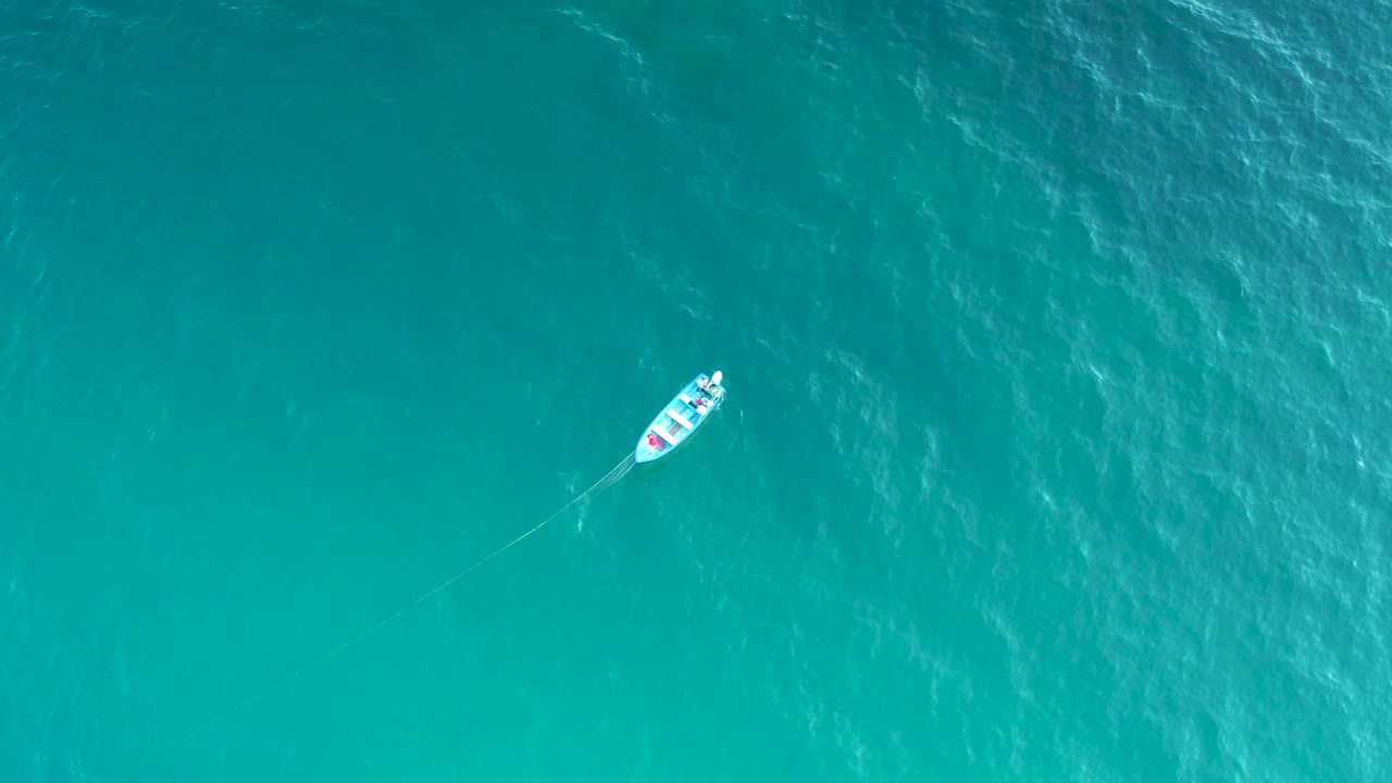 Boat crossing blue ocean with faint wake.