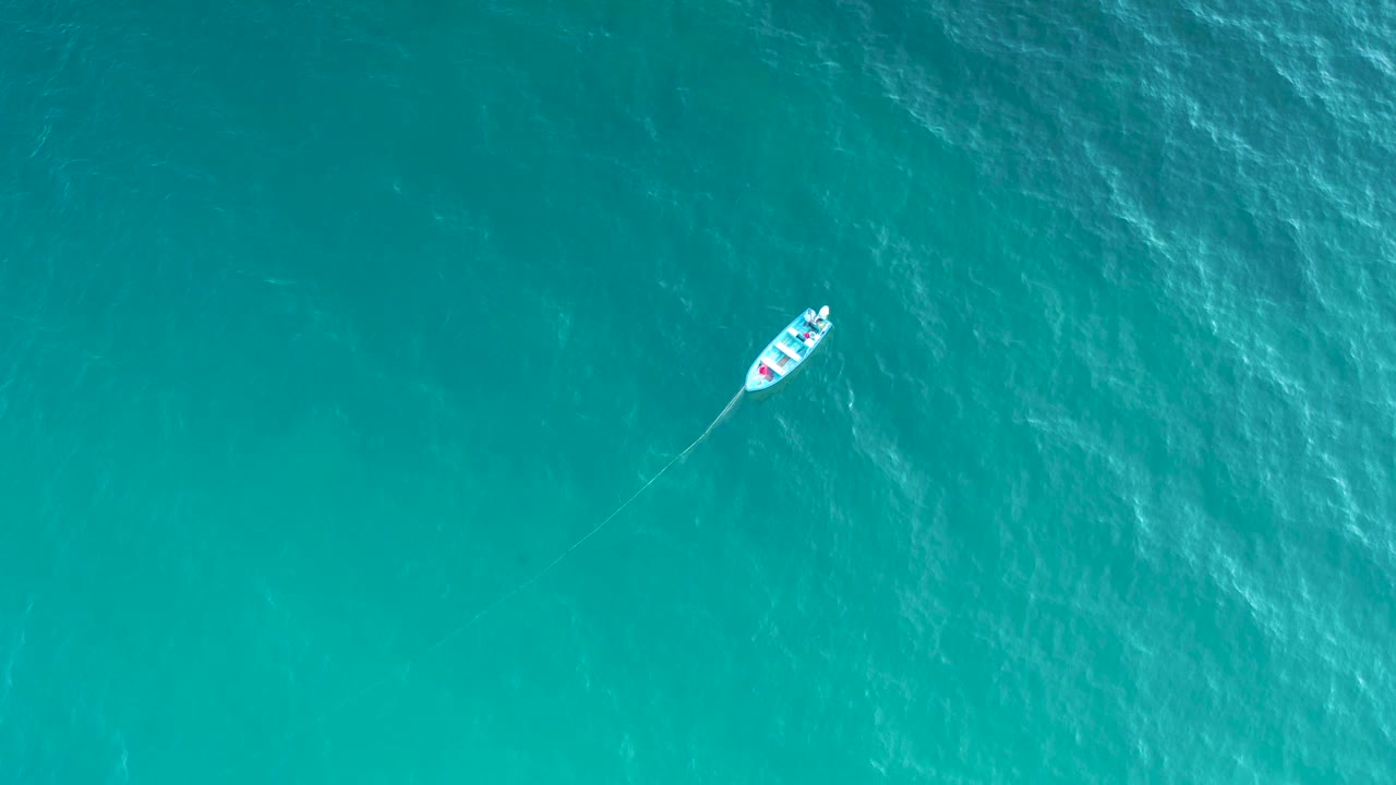 The boat appears near the upper right over deeper turquoise water in El Sargento La Ventana, Mexico, with no land and no visible people.