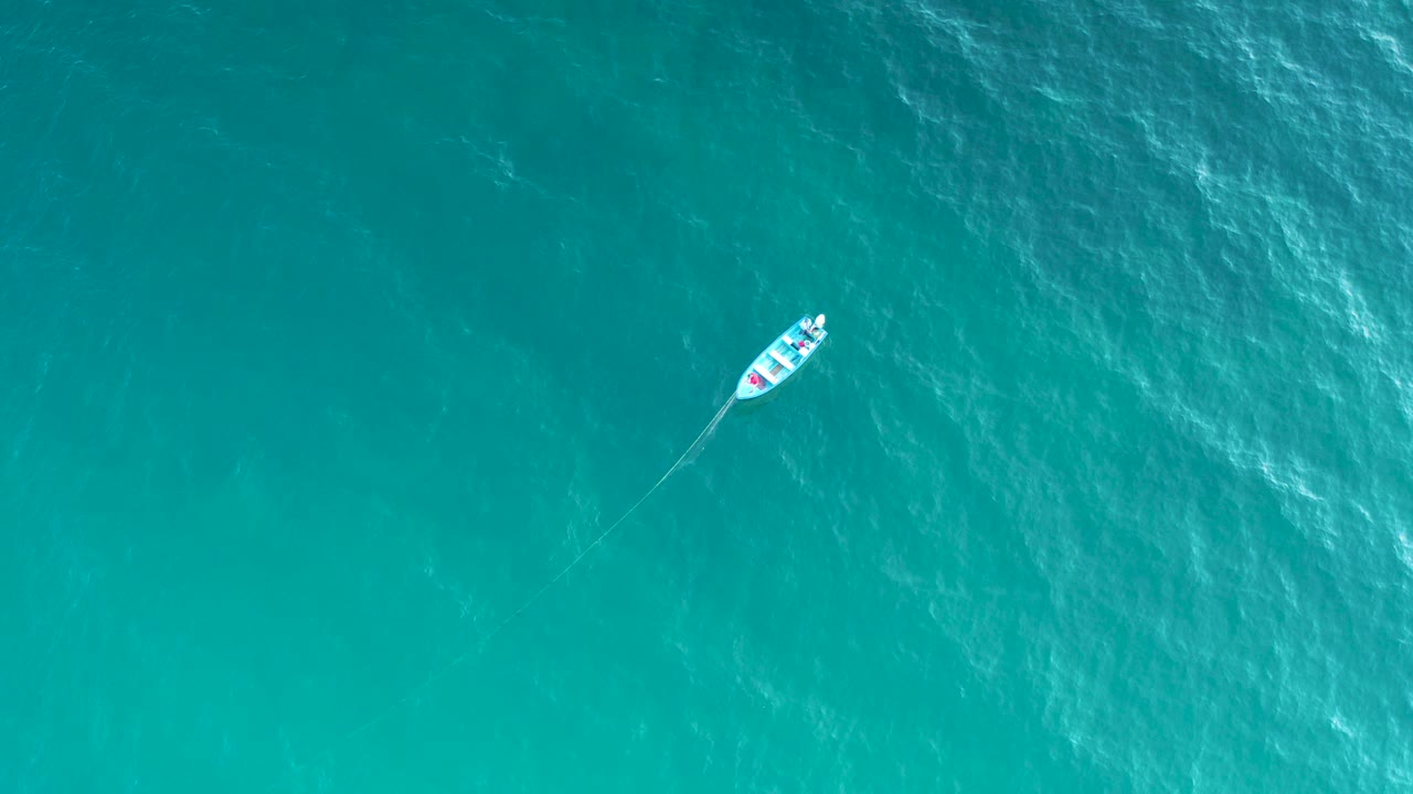 Small boat on turquoise water from above