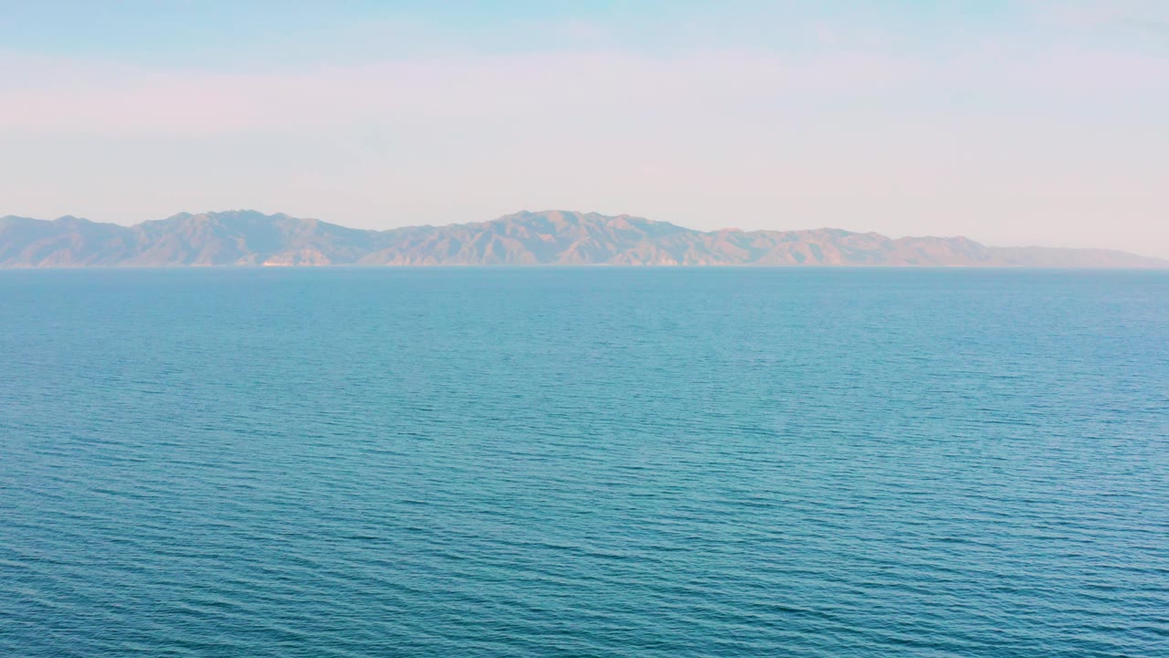 A wide ocean view near El Sargento La Ventana, Mexico shows textured blue water, distant mountains, pale sky, and no visible people.