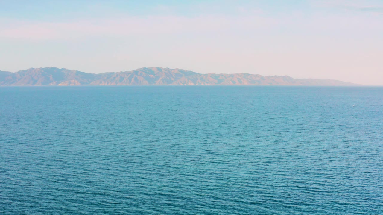 Opening frame of blue ocean off El Sargento La Ventana, Mexico with a low mountain coastline on the horizon and no visible people.