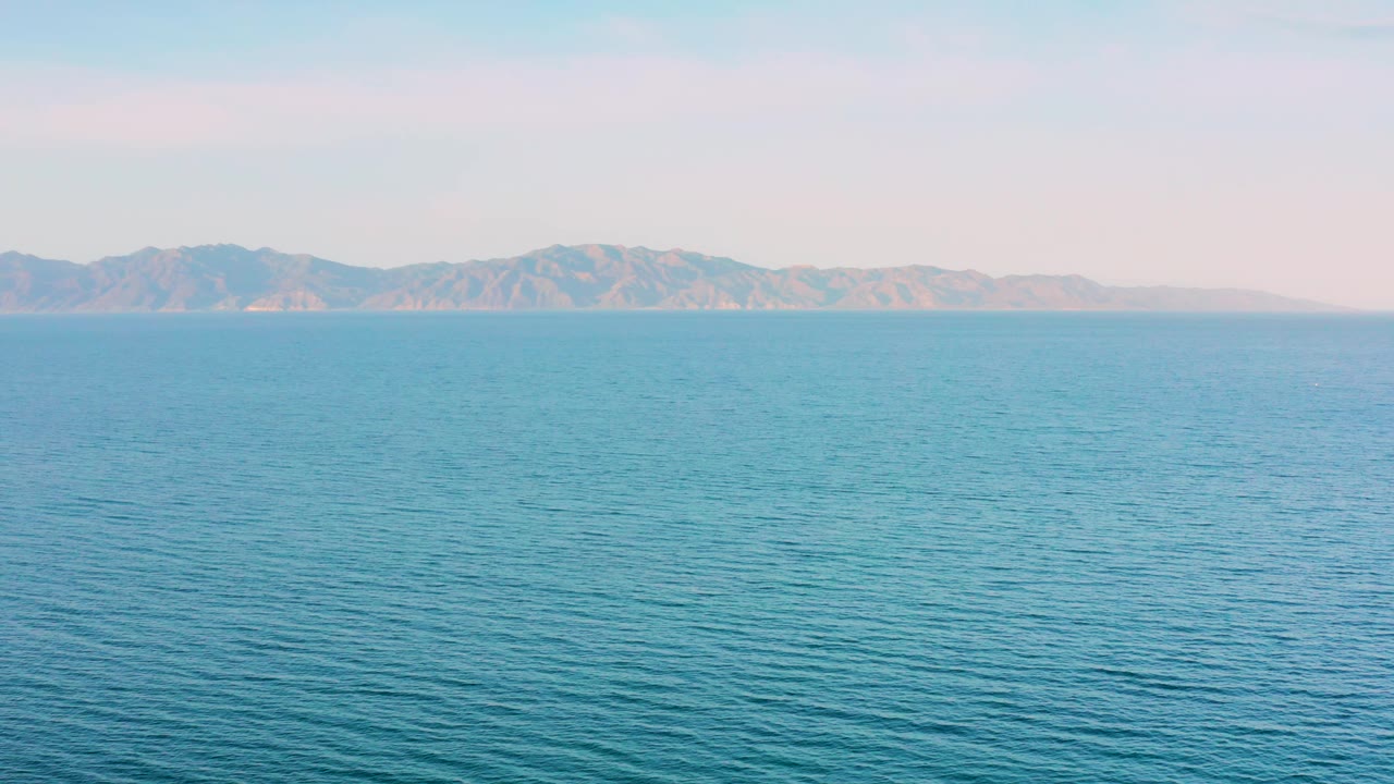 Third frame with blue water stretching toward a rugged mountain coastline near El Sargento La Ventana, Mexico, with no visible people or vessels.