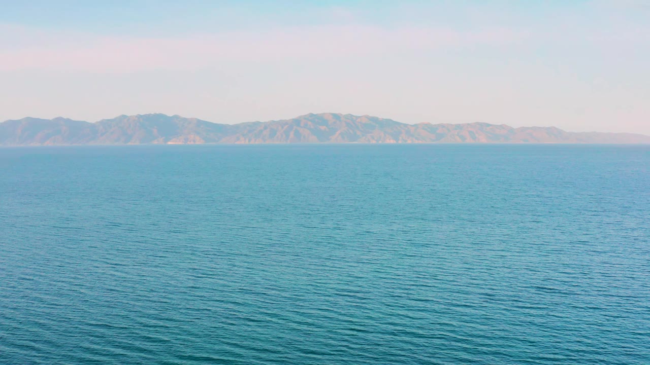 El Sargento La Ventana water view at 0:01, with the ocean surface filling the foreground and a low mountain range across the background, no visible people.