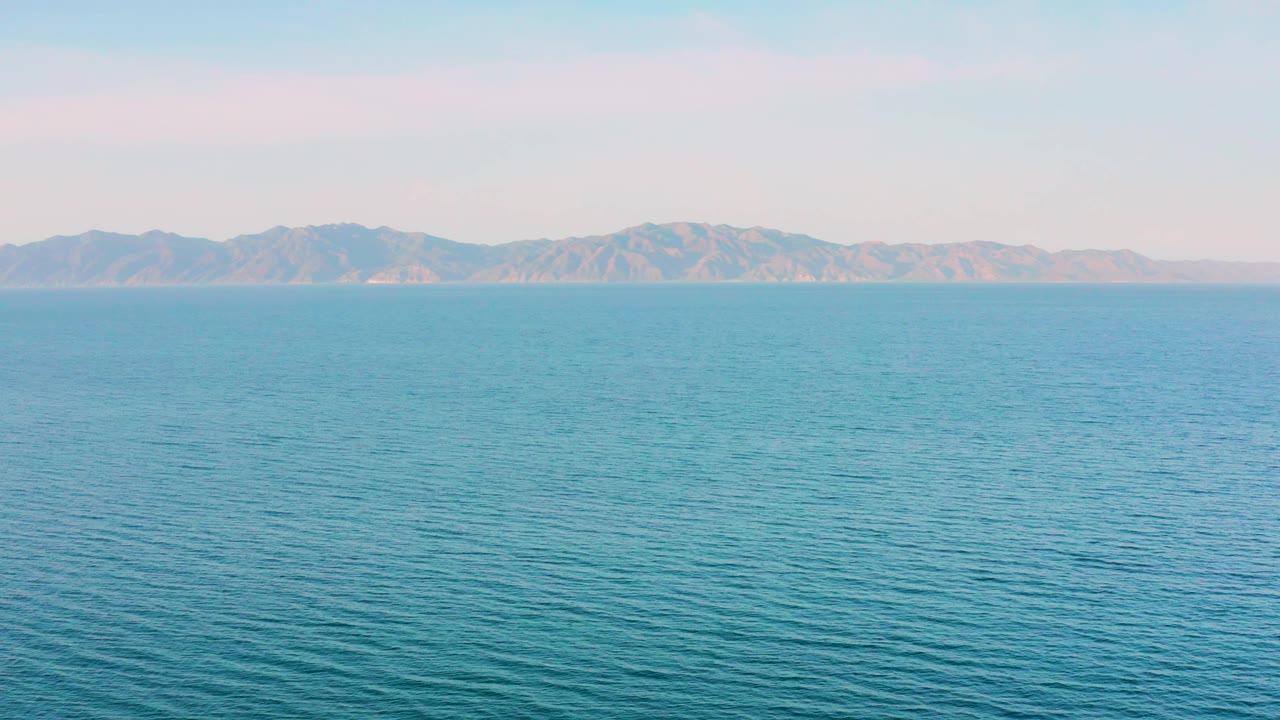 At 0:03, the El Sargento La Ventana ocean remains wide and uncluttered, with soft haze over distant mountains and no visible people or vessels.