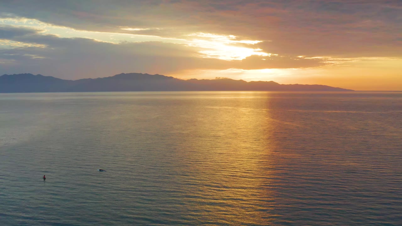 At 0:01, the sun sits behind bright cloud breaks while a gold reflection widens on the water near the center of the El Sargento La Ventana frame, with no visible people.