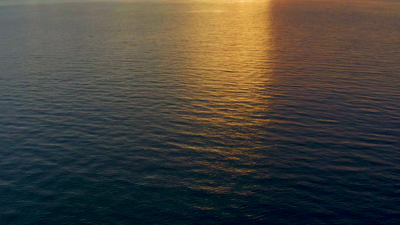 Golden sunset reflection spreads across dark blue-green rippled ocean water in El Sargento La Ventana, Mexico, with no visible people.