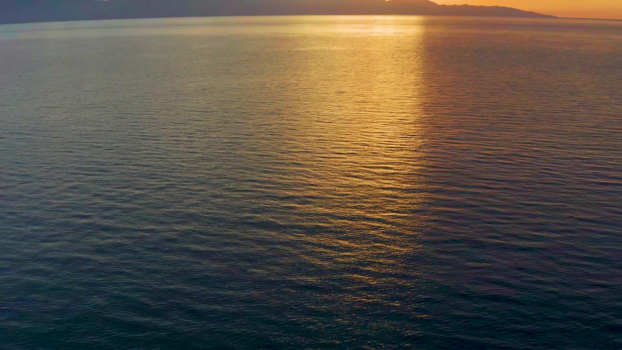 Second frame in El Sargento La Ventana shows the sun reflection centered over textured blue-green water, with silhouetted mountains across the top and no visible people.