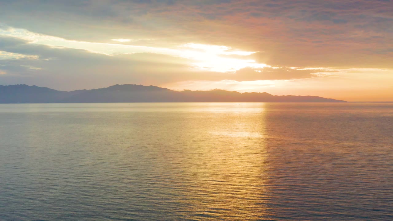 At 0:03, the mountain line stretches across the horizon in El Sargento La Ventana while cloud-filtered sunlight falls onto smoother-looking water, with no visible people.