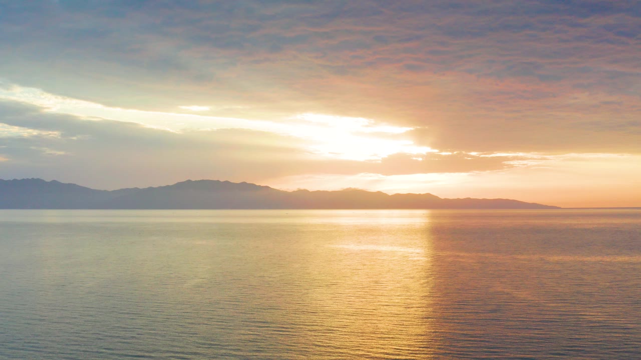 Sunset over calm ocean with distant mountains