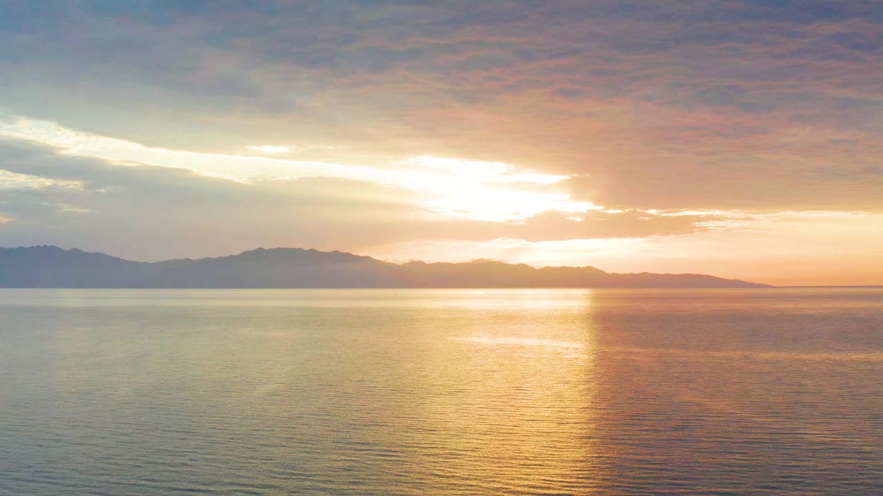 Early frame in El Sargento La Ventana, Mexico, showing rippled ocean water under a low sun, with a bright vertical reflection and no visible people.
