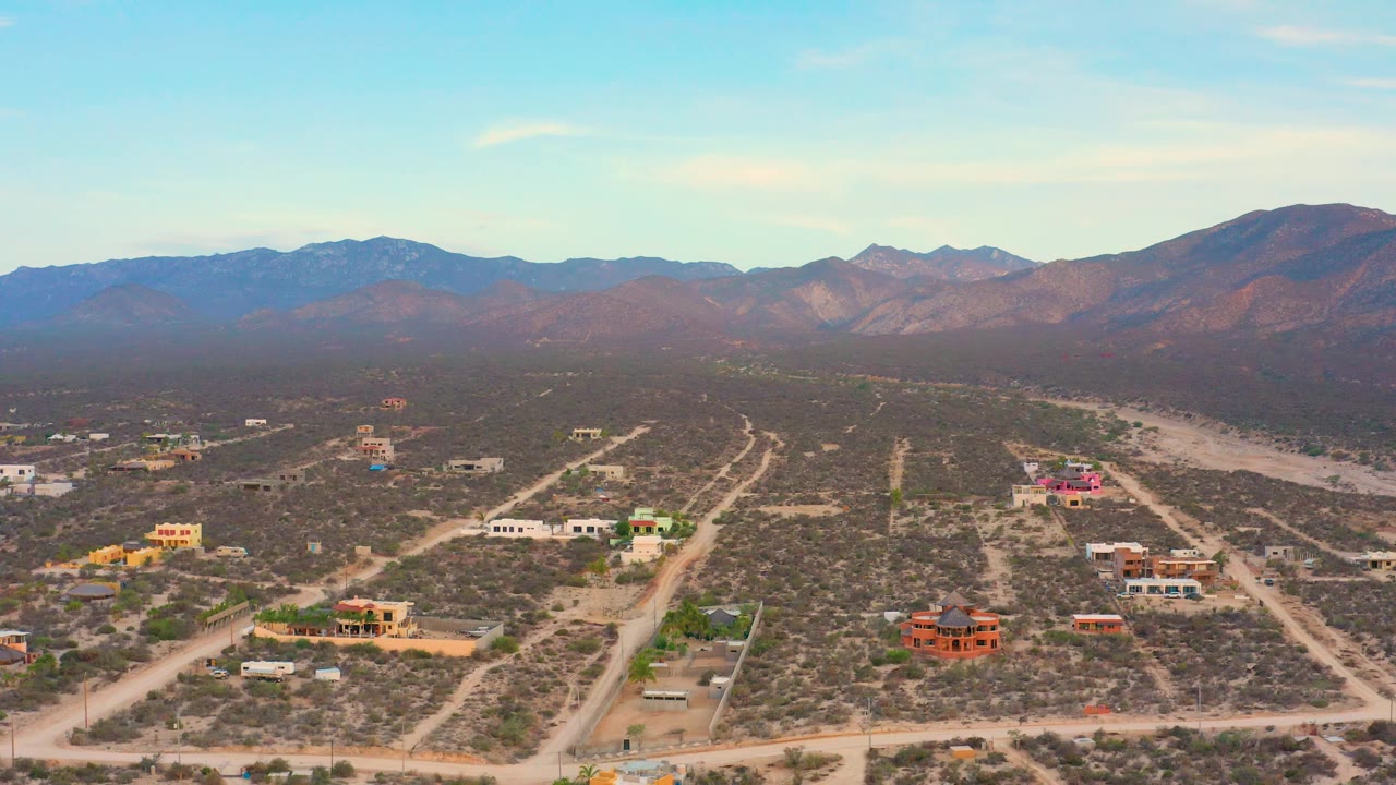 Aerial village view with a dry wash curving near scattered homes and roads.