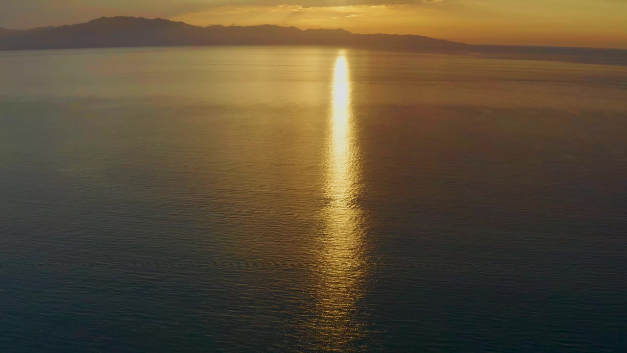 Bright vertical sunset reflection stretching across smooth sea