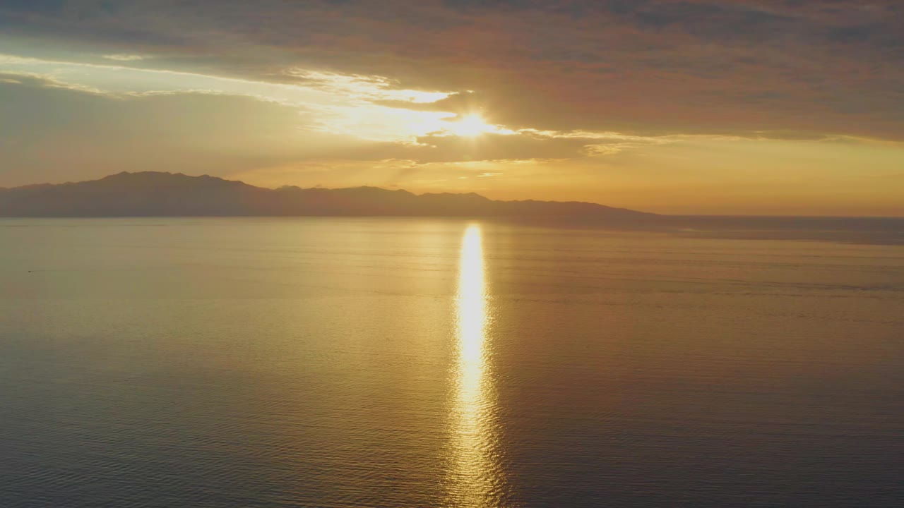 The second frame holds the sun near the upper center as gold light forms a narrow column across the water toward the foreground in El Sargento La Ventana, with no visible people.