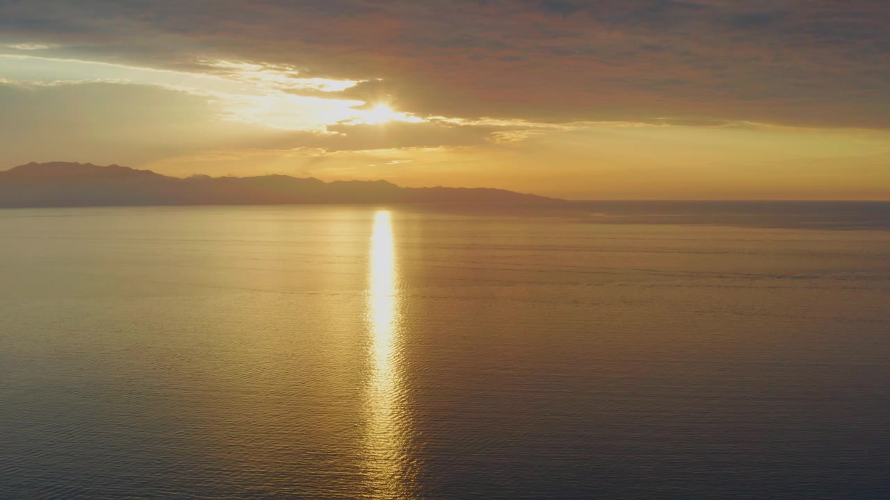 At 0:02, the orange sky and cloud bank frame the setting sun above open water in El Sargento La Ventana, Mexico, with mountains along the horizon and no visible people.