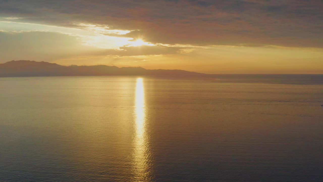 At 0:01, the sun sits just under a dark cloud shelf over El Sargento La Ventana water, with the reflection forming a narrow bright column and no visible people.