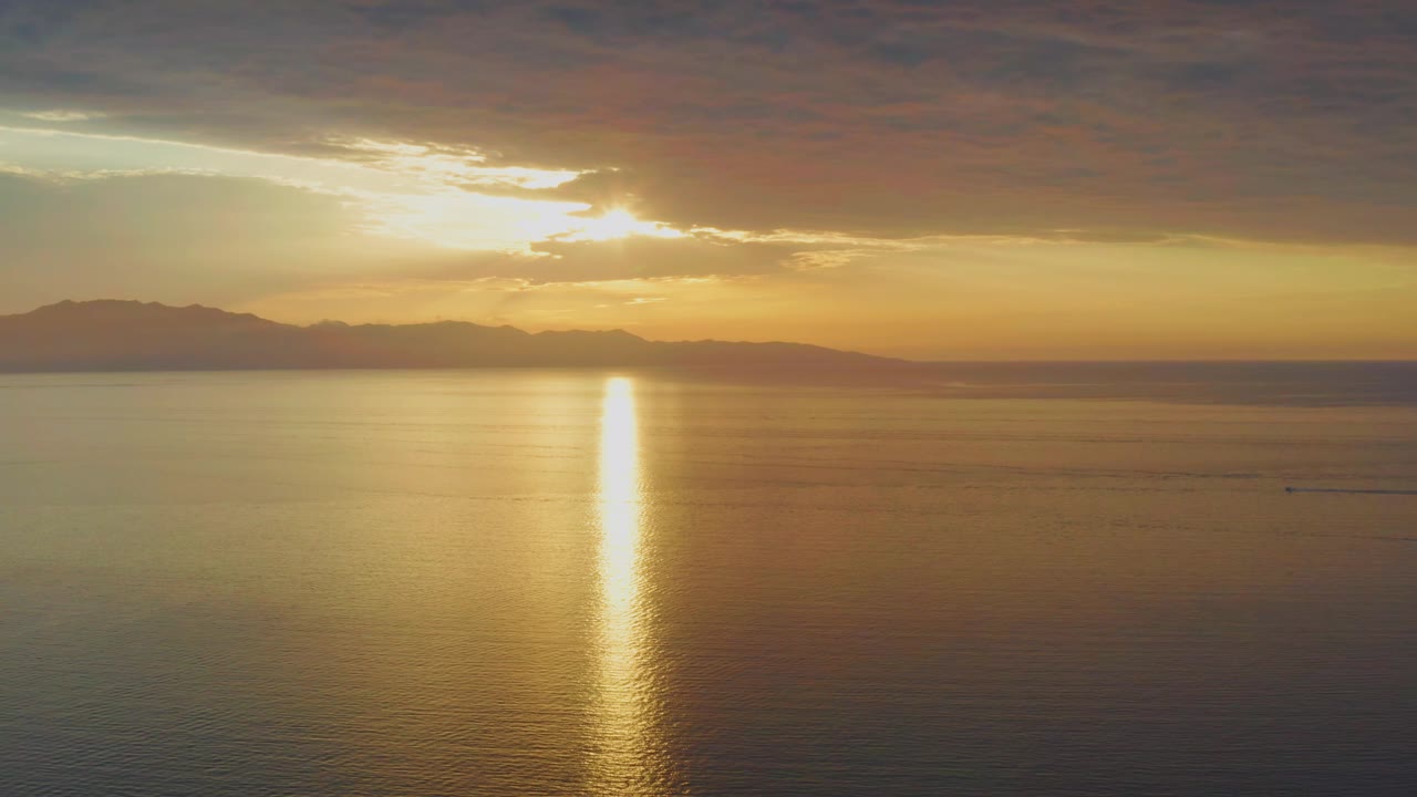 At 0:01, the sun reflection sits near the center of the calm ocean while dark clouds frame the bright sky above El Sargento La Ventana, Mexico, with no visible people.