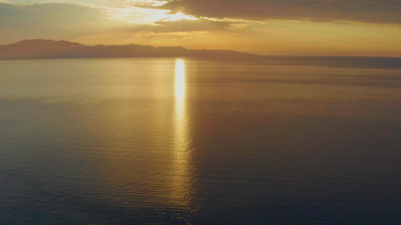 One second into the El Sargento La Ventana sunset, the sun reflection remains centered on rippling water below a dark horizon line, with no visible people.