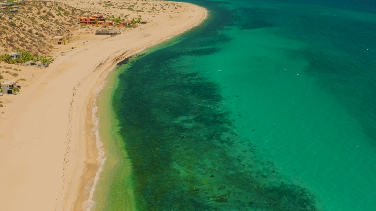 Curving beach edge with shallow green water from above