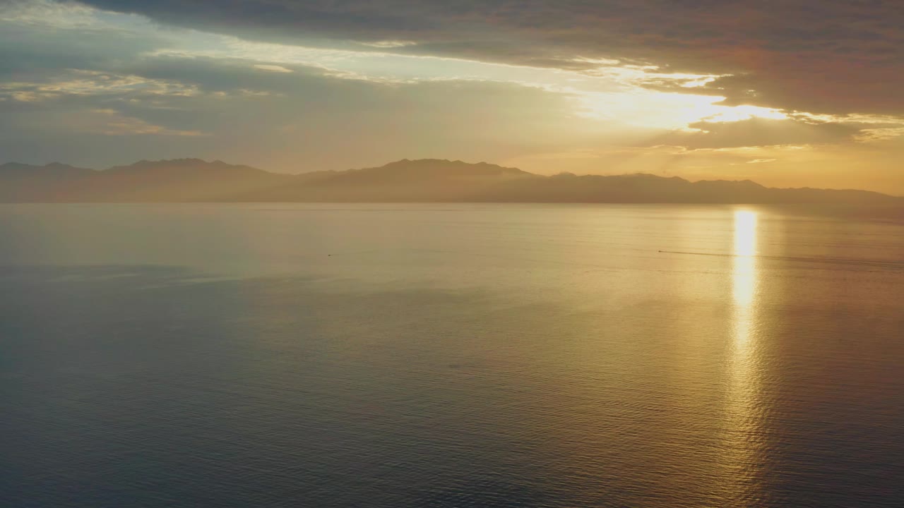 One second in, the sun streak sits near the right side of the water while distant hills and broken clouds hold across the El Sargento La Ventana horizon, with no visible people.