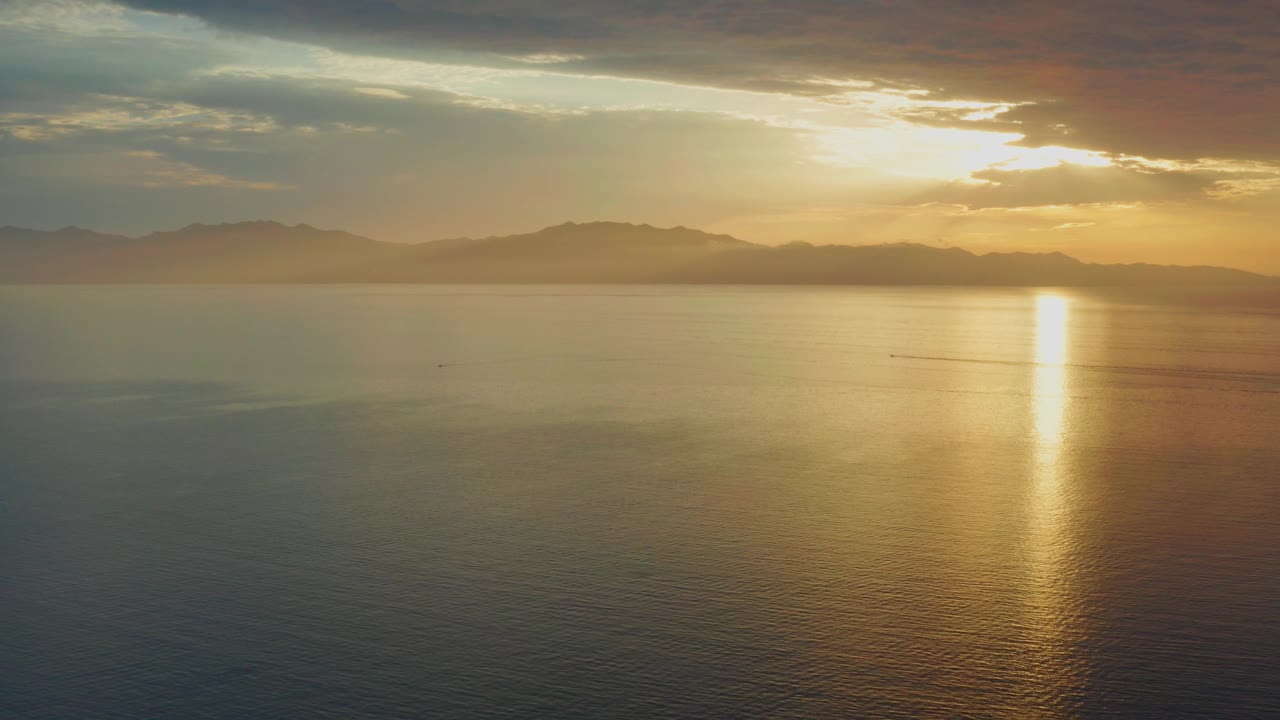 Mid-clip frame of smooth sea water and a strong golden reflection near El Sargento La Ventana, Mexico, with distant mountains and no visible people.