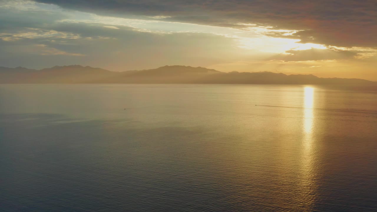 Golden sunset reflection stretches down the open water near a distant mountain horizon in El Sargento La Ventana, Mexico, with no visible people.