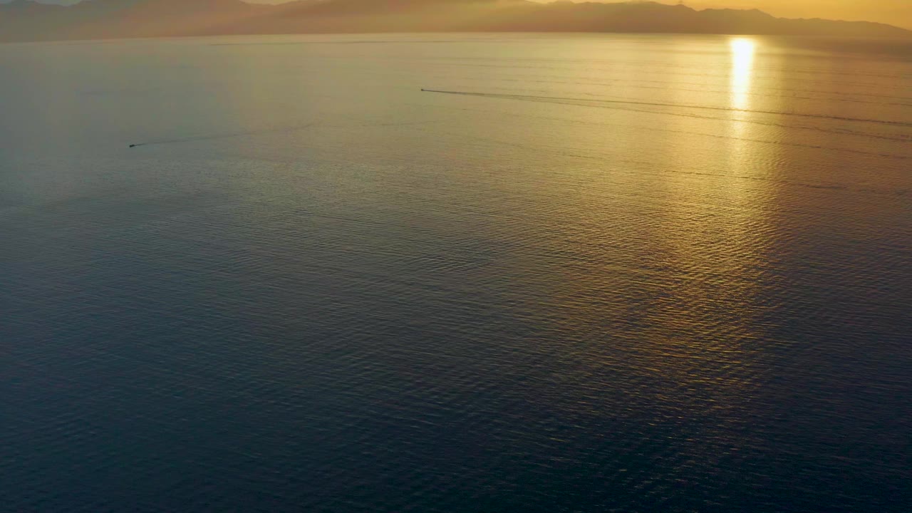 Golden sunlight reflecting on open sea with distant horizon