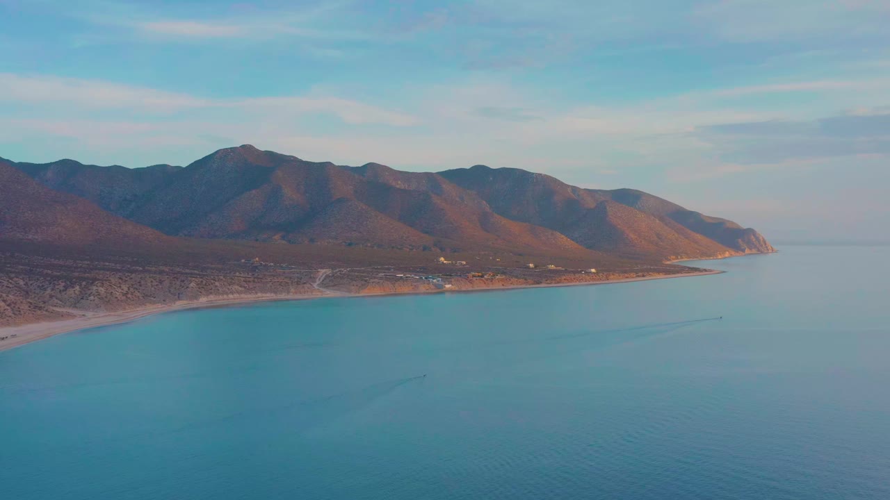 Aerial coastline with calm blue water and mountain ridge