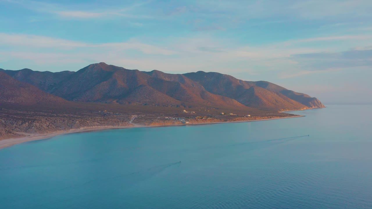 Blue water foreground with mountain shoreline under a pale sky.