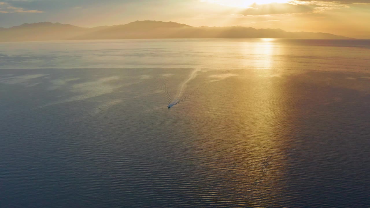 At this moment in El Sargento La Ventana, Mexico, the boat remains small against a wide ocean field, with rippled foreground water, a pale wake, and no visible people.
