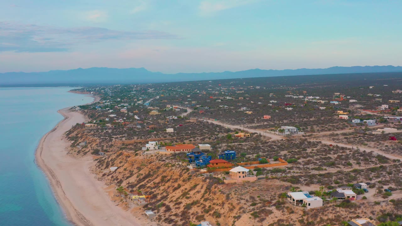 Aerial coastline view with beach on the left and scattered houses inland