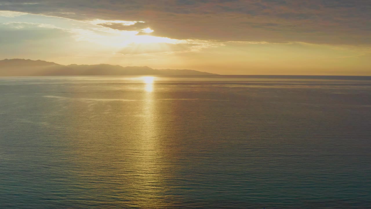 Second frame shows the low sun breaking through clouds above open water in El Sargento La Ventana, Mexico, with the reflected light centered on the sea and no visible people.
