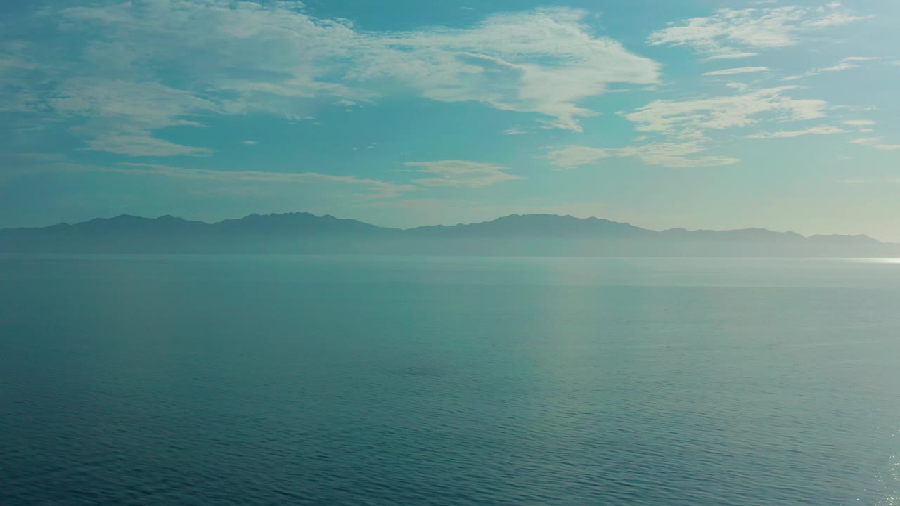 Open water fills the foreground while fog mutes the shoreline and mountains in El Sargento La Ventana, Mexico, with stronger brightness toward the right and no visible people.