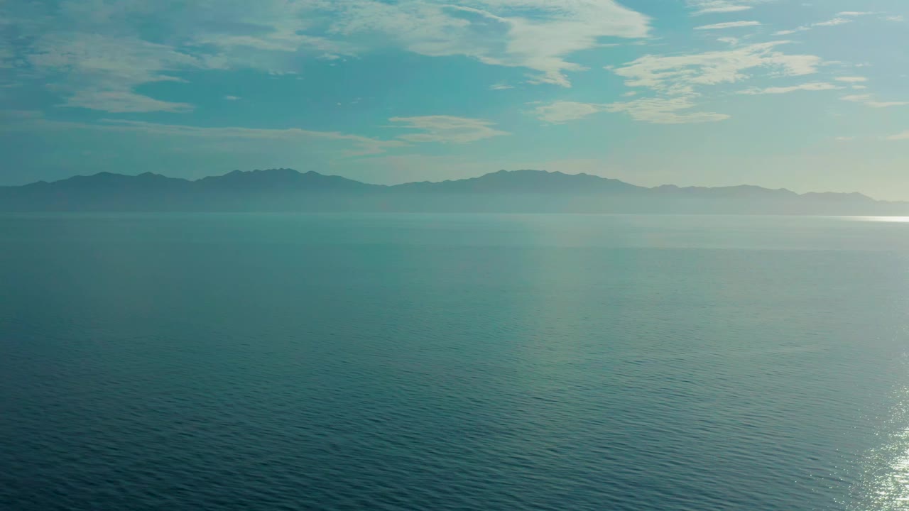 Second frame shows the same elevated view in El Sargento La Ventana, Mexico, with rippled water below, low haze over the mountain line, and no visible people.