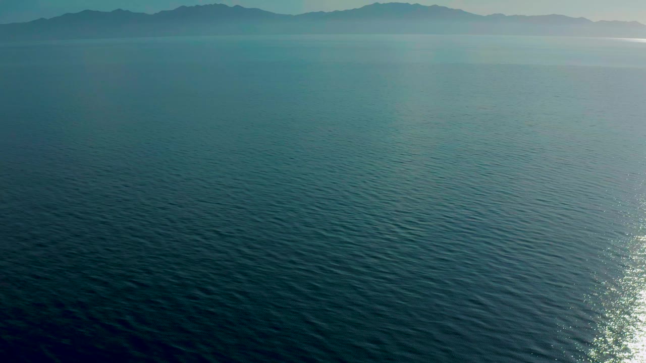 Open sea beneath hazy mountains
