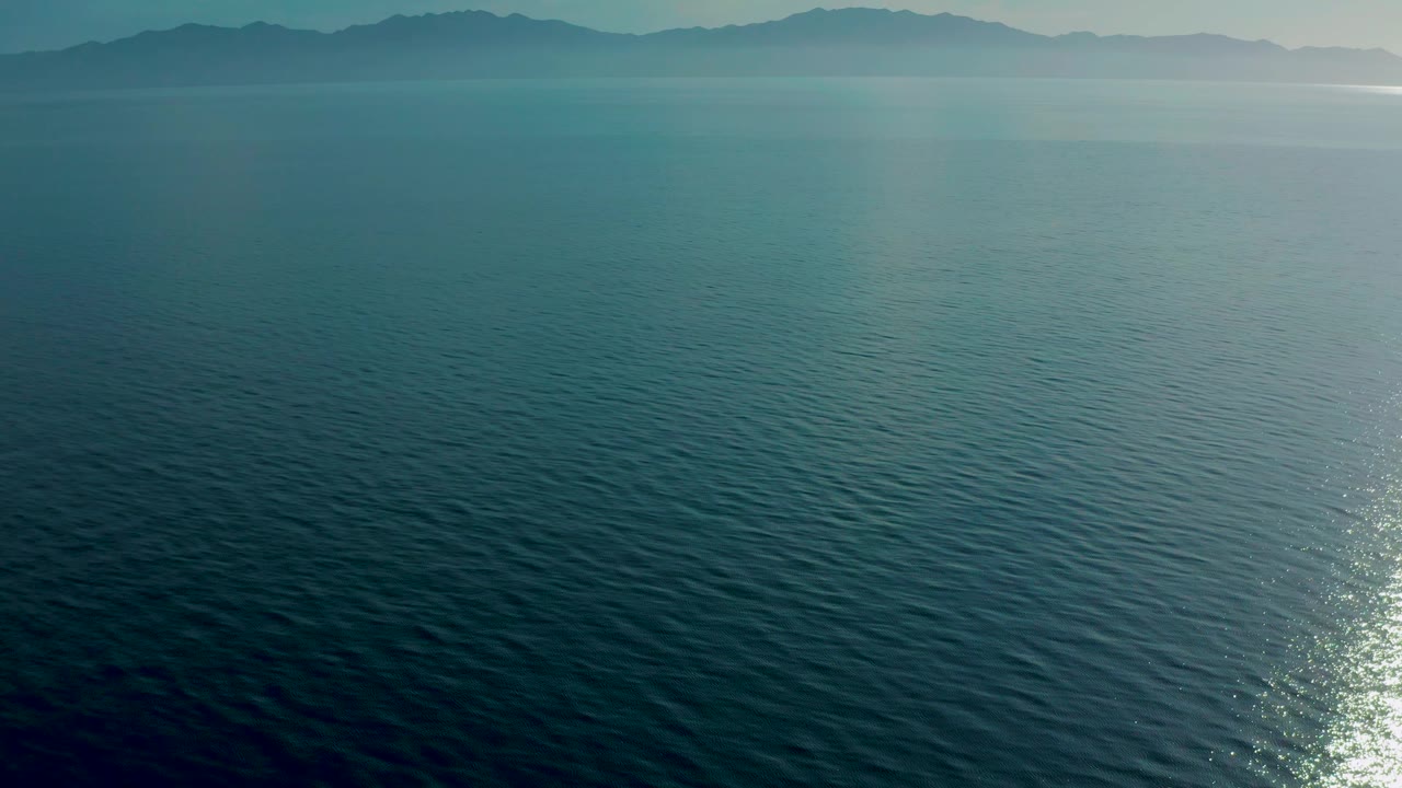 Teal water fills the foreground and midground while soft blue-gray mountains sit on the horizon in El Sargento La Ventana, Mexico, with no visible people.