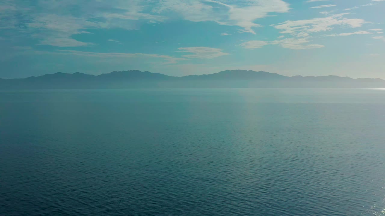 Second frame shows the same El Sargento La Ventana ocean horizon, with soft haze over the distant land and no visible people.