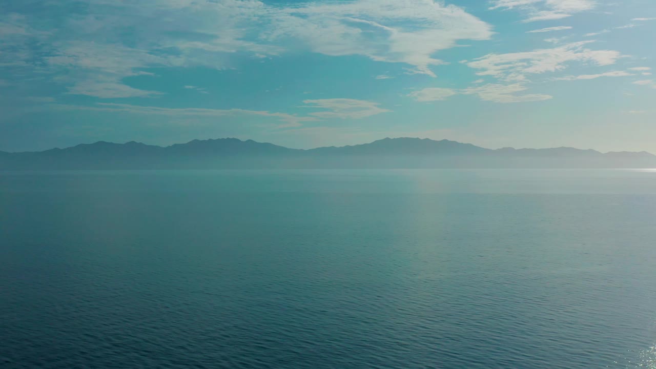 Fourth frame in the El Sargento La Ventana clip shows a broad ocean surface, softened mountain silhouettes, high cloud streaks, and no visible people.