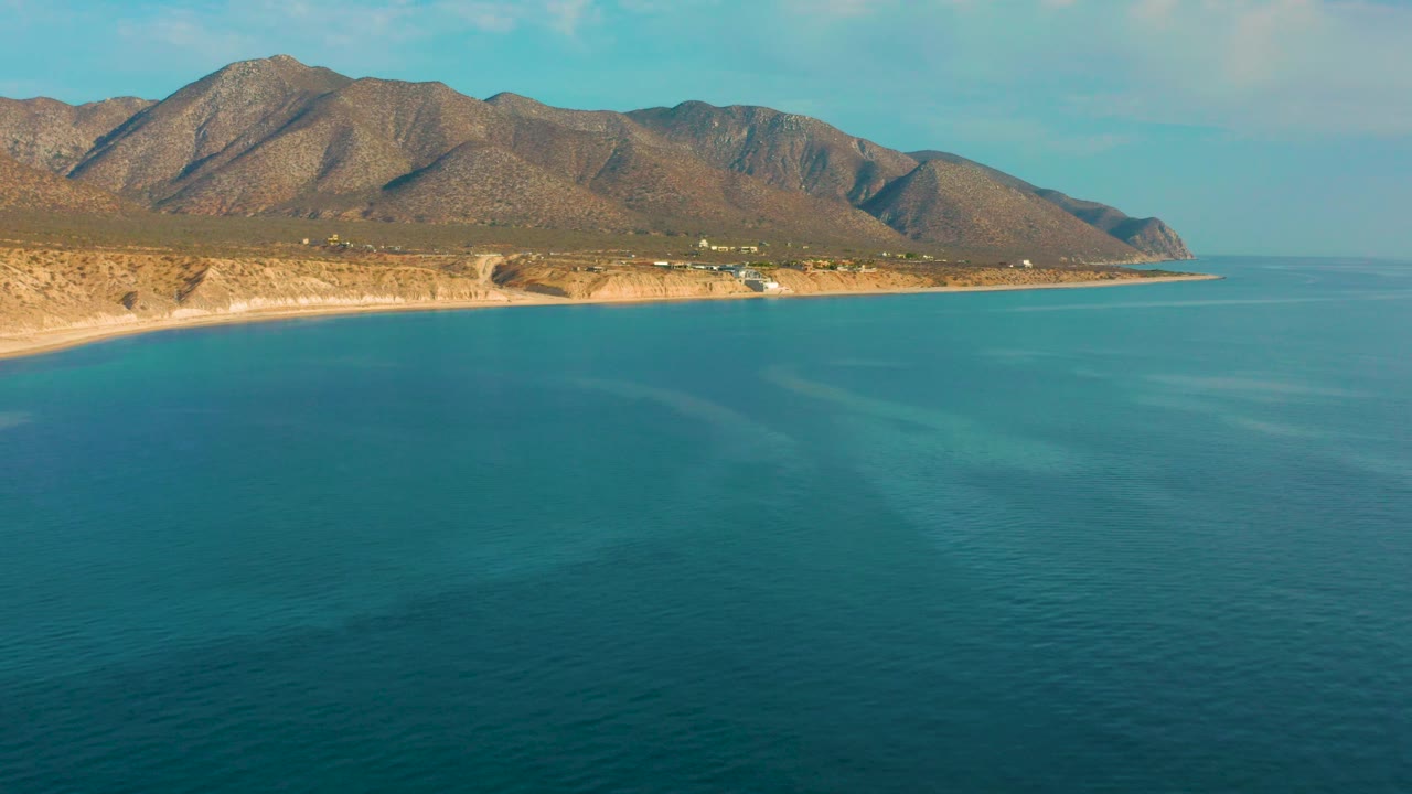 Aerial coastal view with calm ocean, beach, and mountains