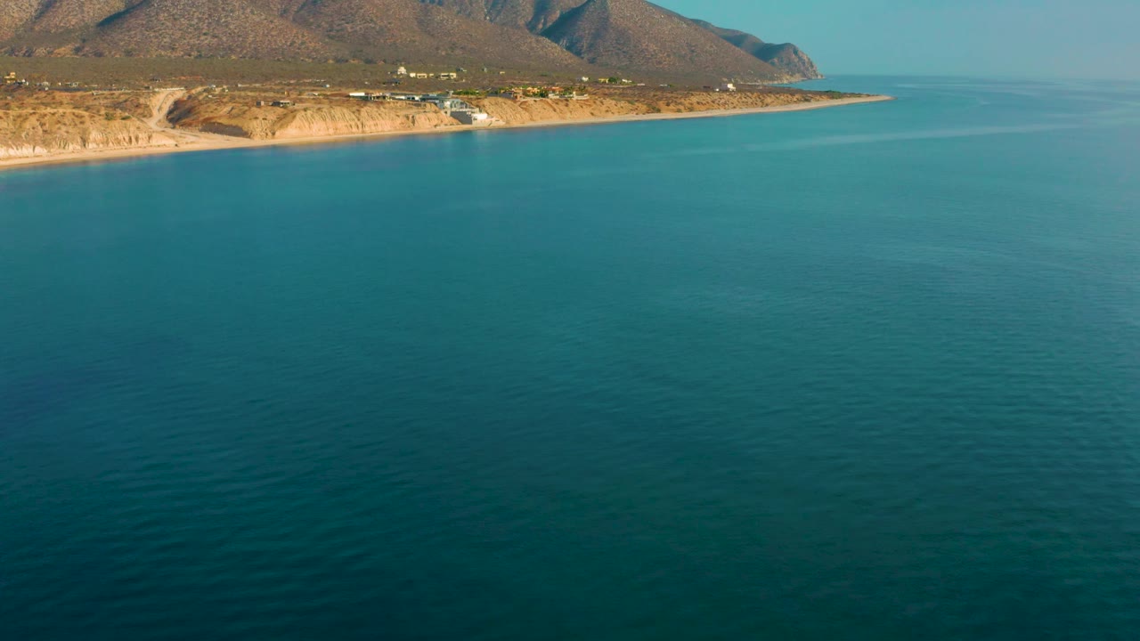 Ocean foreground with sandy shoreline and mountains along the upper frame.